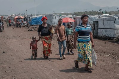 A woman walks through the Bushagara displacement site with four of her children.